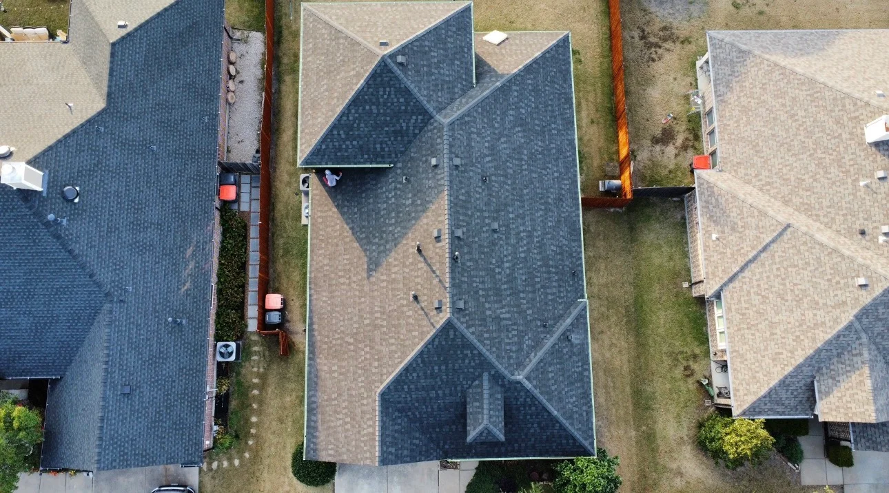 Aerial view of residential home with newly installed multi-pitch asphalt shingle roof in charcoal gray