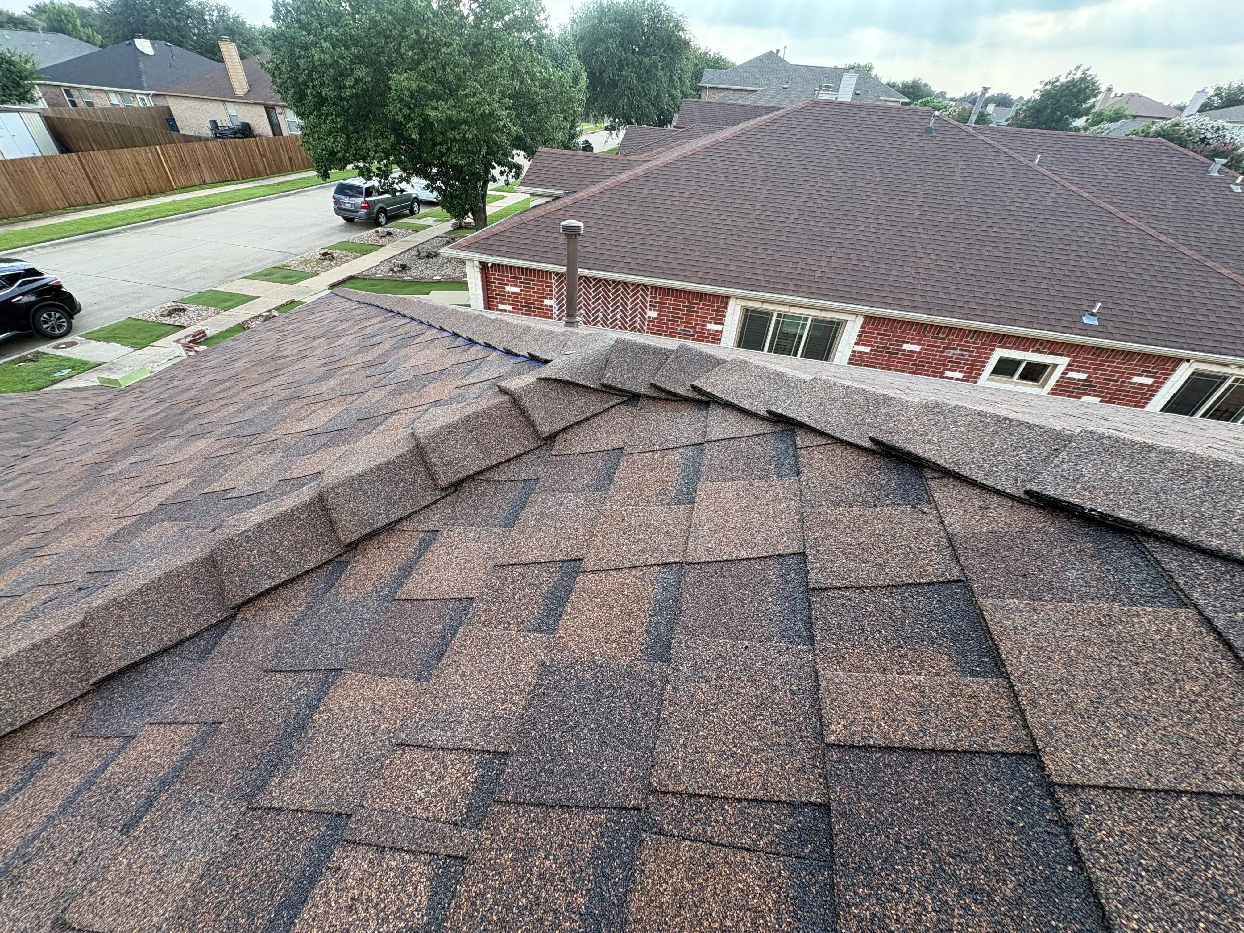 New architectural shingle roof with brown and gray tones on brick residential home