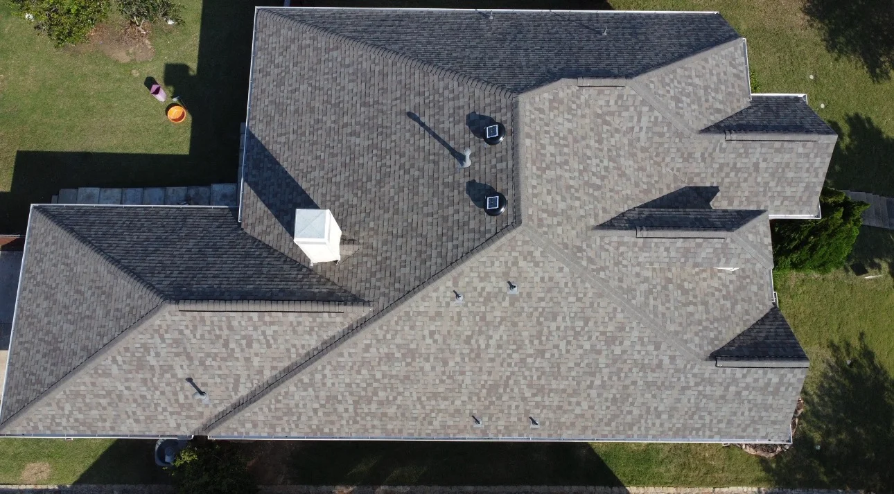Aerial view of newly installed asphalt shingle roof on residential home with multiple peaks