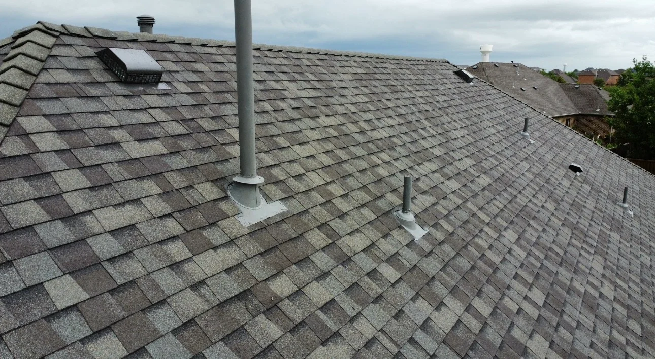 Newly installed gray architectural shingle roof with white flashing and multiple roof vents