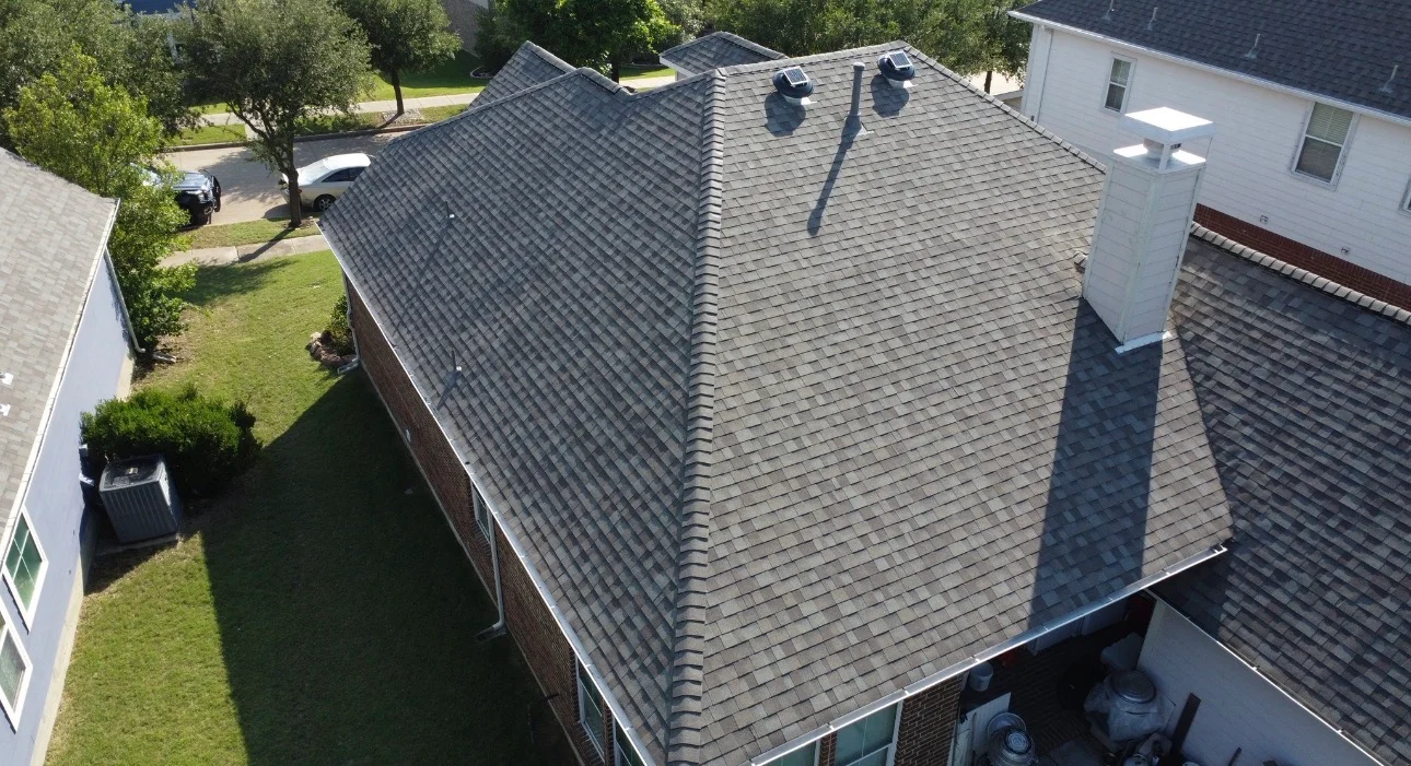 Aerial view of newly installed charcoal gray architectural shingle roof on two-story brick home