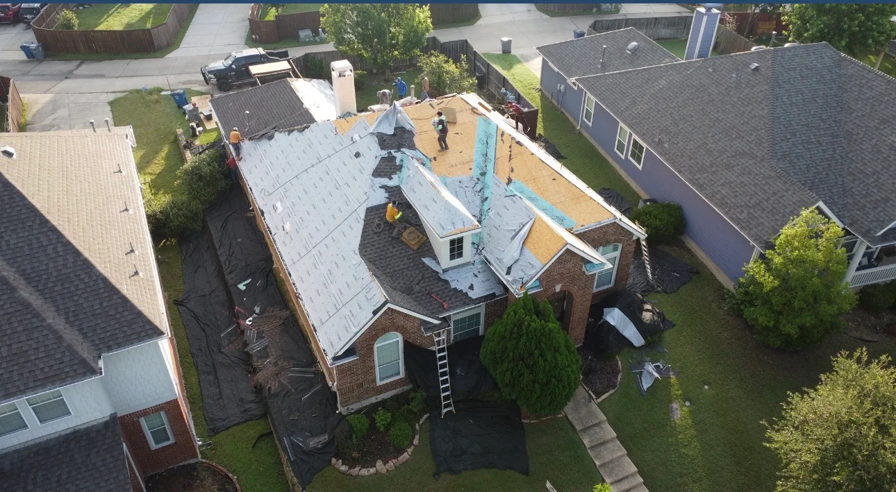 Aerial view of brick home with new roof installation in progress, white underlayment visible