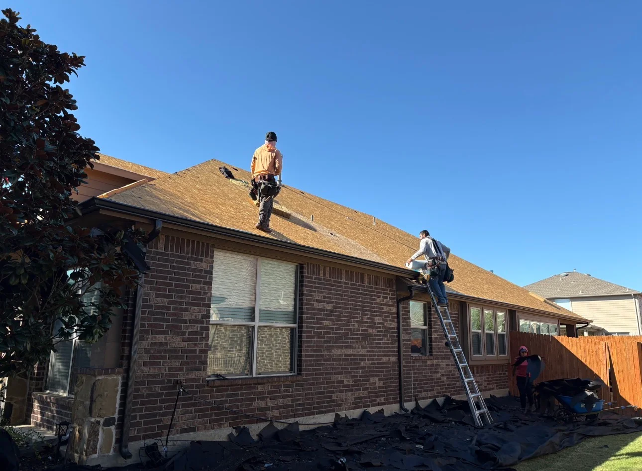 Roofers installing new asphalt shingles on brick home roof in Princeton, TX