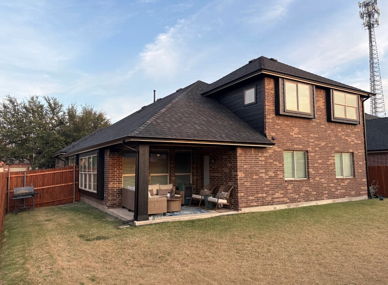 Two-story brick home with new charcoal gray architectural shingle roof and covered patio