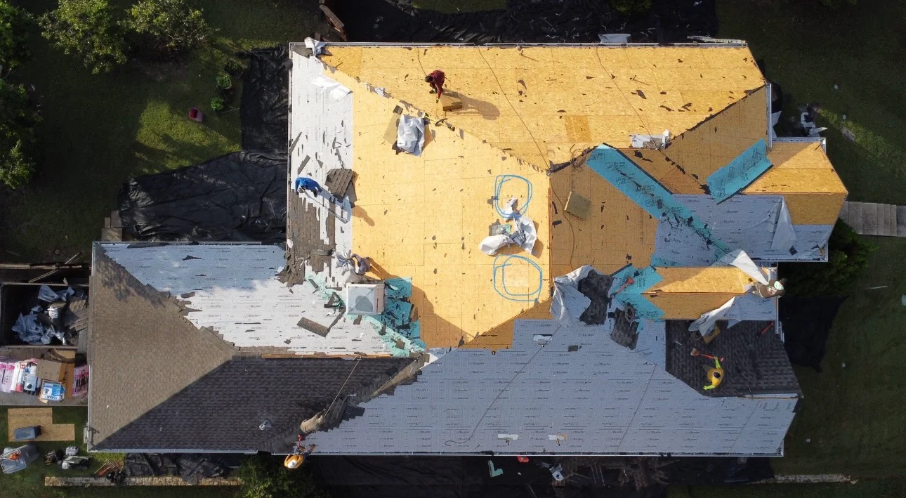 Aerial view of residential roof replacement with yellow sheathing and blue underlayment installed